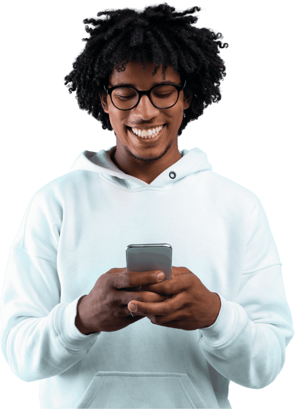 Young man in a white hoodie smiling while reading a text message on his phone